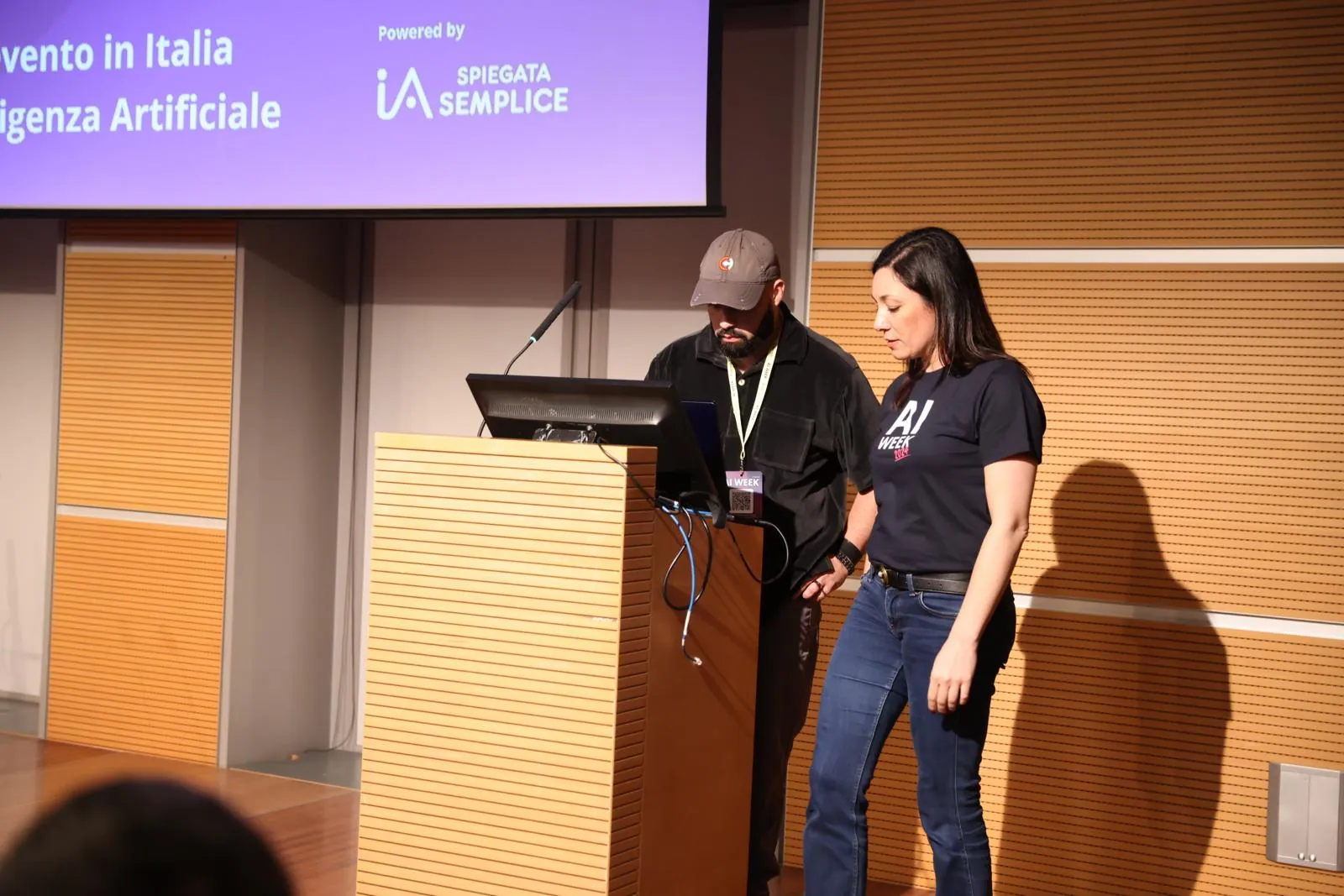 Alessia Preda al leggio del palco di AI Week insieme a un tecnico