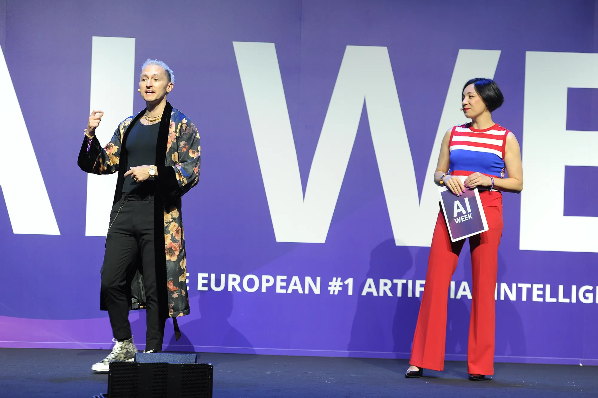 Alessia Preda con la scaletta in mano accanto a uno speaker sul palco di AI Week