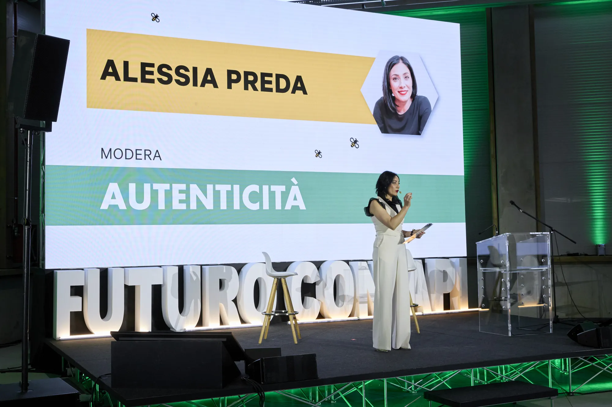 Il palco dell’inaugurazione Conapi con lo schermo che annuncia Alessia Preda come moderatrice del tema Autenticità