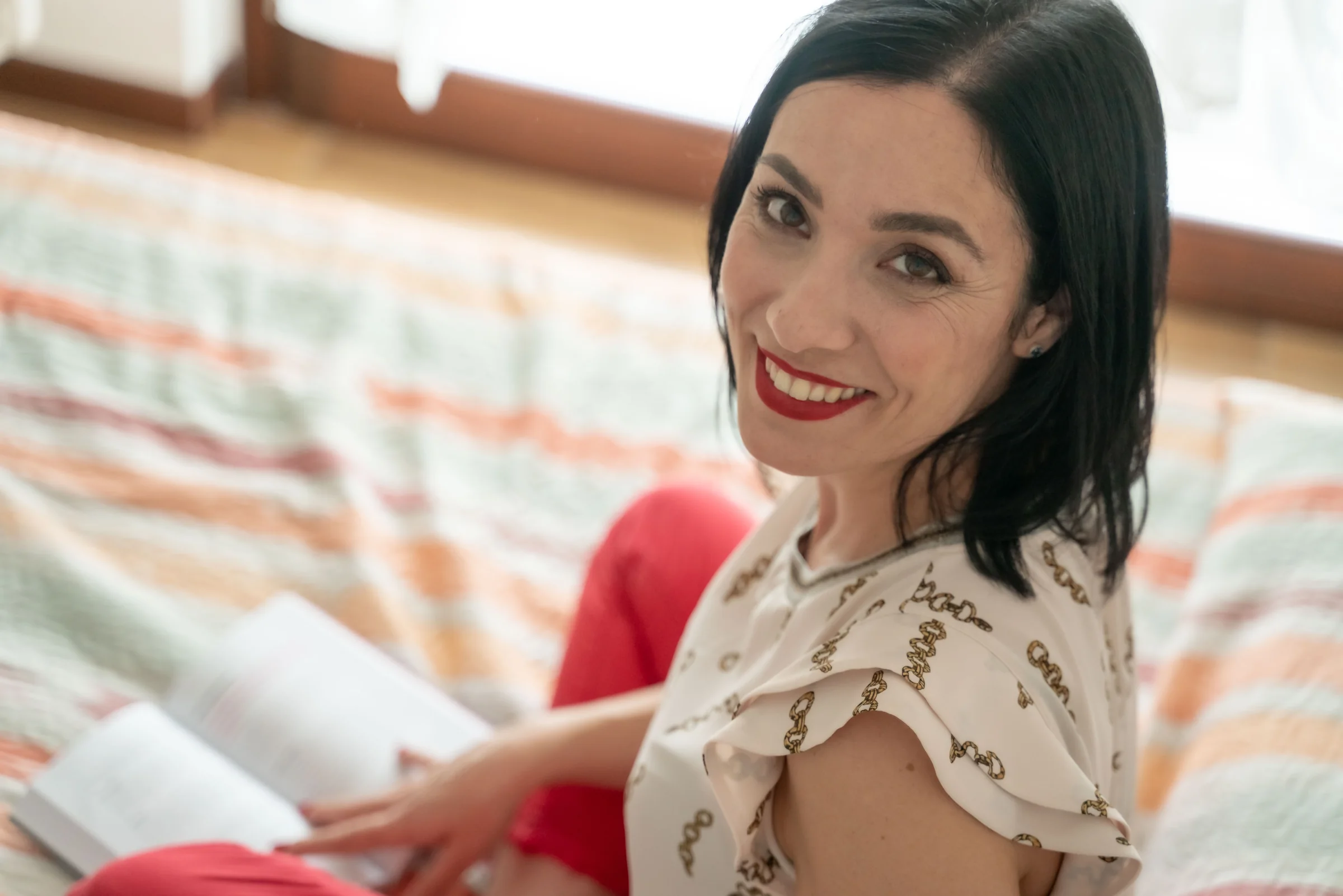 Alessia Preda sorride all’obiettivo, sdraiata sul letto con un libro